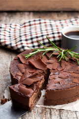 Baked  belgian chocolate cheesecake with chocolate ganache on wooden table