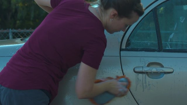 Woman washing the rear door of her car.  Shot on a Blackmagic Ursa Mini Pro 4.6k with a Sigma 50-100mm f/1.8.