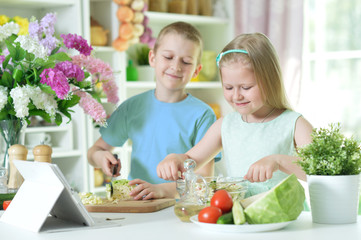 Obraz na płótnie Canvas Cute little brother and sister cutting vegetables