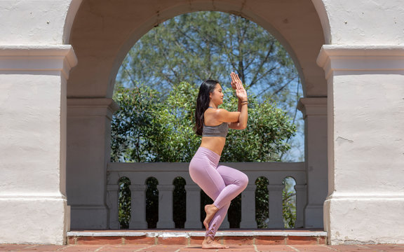 Athletic young woman practicing yoga outdoors, doing Eagle Pose side view