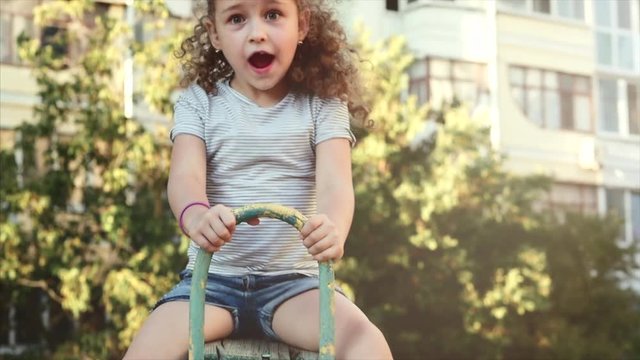Happy young little girl spinning in a swing and smiling