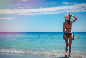 Young caucasian girl in black bikini on a beach in summertime. Odessa, Ukraine