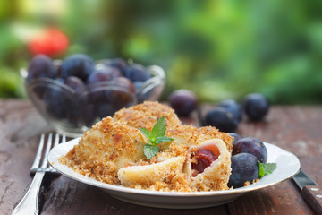 Closeup of a plate with delicious sweet plum dumplings. Outdoor image with green background.