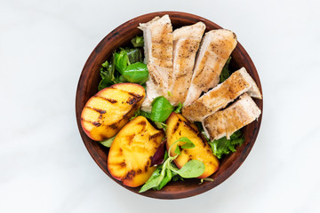 Chicken salad with grilled peach and mixed salad in a bowl. healthy food