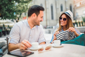 Beautiful loving couple sitting in a cafe enjoying in coffee and conversation after shopping