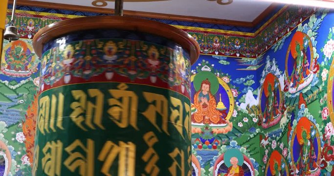 Buddhist art and decoration in ancient temple of Ladakh. Spinning prayer wheel in monastery