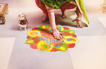 Women coloring traditional rice art (Rangoli) for indian marriage rituals