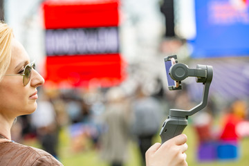the girl with the phone on the stabilizer leads the videoblog. She takes herself to the camera Smartphone