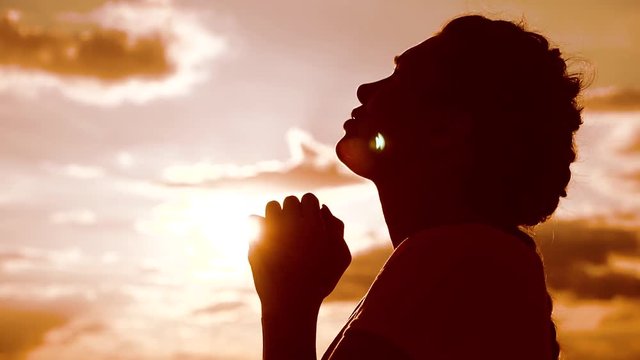 the girl prays. Girl folded her hands in lifestyle prayer silhouette at sunset. slow motion video. Girl folded her hands in prayer pray to God. girl praying asks forgiveness for sins of repentance