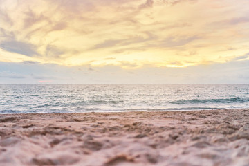 Fototapeta premium Colourful beach sunset with orange sky, Low angle with blurry sand in foreground