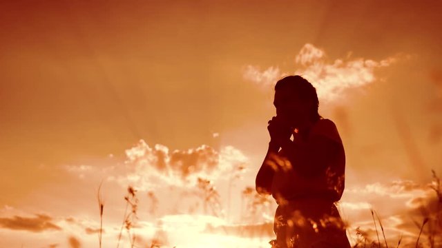 woman praying lifestyle on her knees. Girl folded her hands in prayer silhouette at sunset. slow motion video. Girl folded her hands in prayer pray to God. the girl praying asks forgiveness for sins