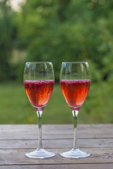 Celebrating/Two glass of cold champagne with raspberries on the old wooden table outdoors