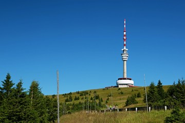 Red and white telecommunication and lookout tower Praded, Czech Republic, Europe standing in Jeseniky mountains, tourists hiking on road, sunny summer day, clear blue sky, green trees