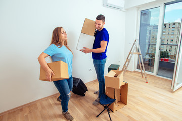 Image of young man and woman with cardboard box. Young family moving in a new apartment concept.