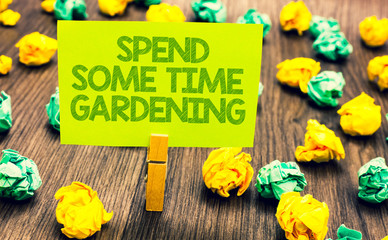 Handwriting text Spend Some Time Gardening. Concept meaning Relax planting flowers fruits vegetables Natural Paperclip retain written words yellow paper paper lobs laid on wooden floor.