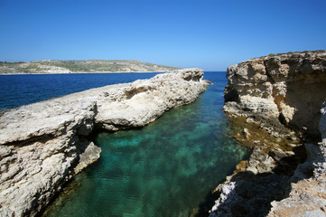 Rocky cliffs of Blue Lagoon in Comino, Malta during the sunny summer day