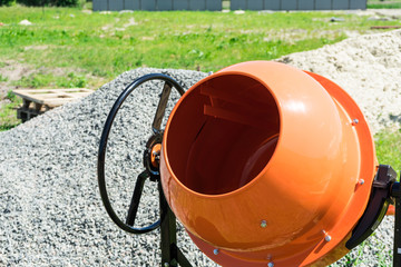 Photo concrete mixer installed on the construction site next to a pile of sand and gravel.