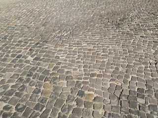 Uneven cobblestone pattern in road in sunshine