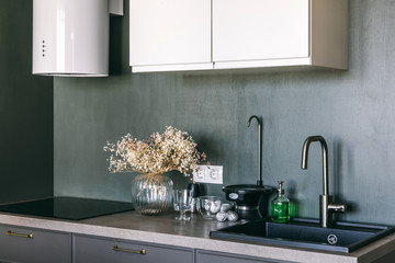 New stylish bright scandinavian interior details. Dark grey kitchen room organization. Pure water and clear sink
