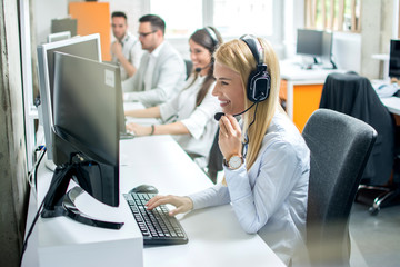 Attractive young woman working in a call center with her colleagues