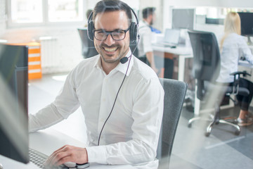 Cheerful customer support representative  with headset working in call center