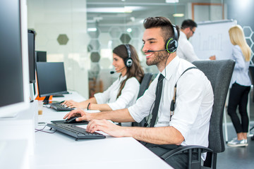 Smiling handsome call center operator in headset working at office
