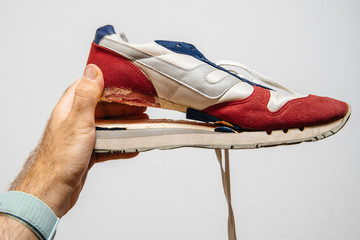 POV at hand holding against white background one sport footwear sneaker with broken sole - quality...