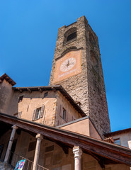 Fototapeta na wymiar Bergamo, Italy - May 10, 2018: Bell tower, clock tower. Ancient architecture of Old town or Upper City in Bergamo. Medieval bell tower with clock in Bergamo