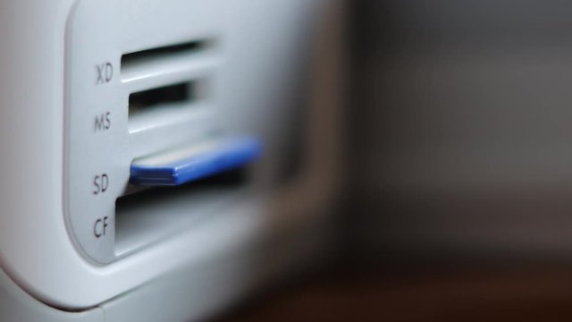 An Elderly Man Plugging SD Memory Flash Card Into A Slot Of Printer