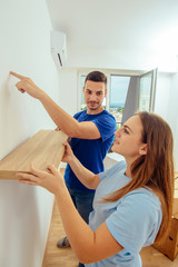 Fototapeta premium Dorosły facet montuje półkę na ścianie. Koncepcja dekoracji i renowacji domu.