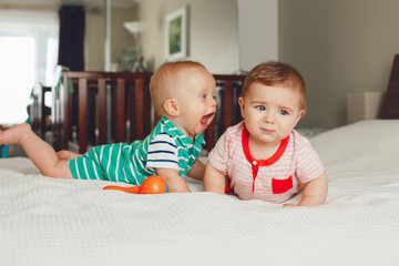 Group portrait of two white Caucasian cute adorable funny baby boys lying together on bed...