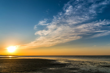 Fototapeta premium beautiful sunset over the sea shore with clouds reaching the horizon