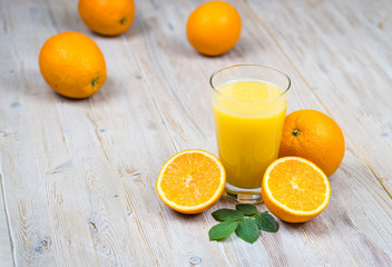 oranges on a wooden background and a glass with juice