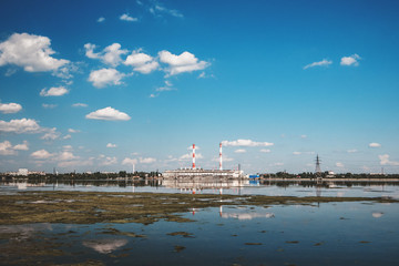 Electricity power plant on river or reservoir with bright blue sky, industry landscape 