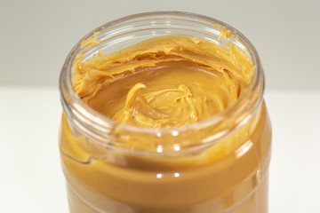 A jar of organic peanut butter sitting on the kitchen table waiting to be eaten 