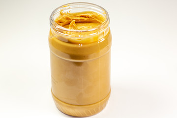 A jar of organic peanut butter sitting on the kitchen table waiting to be eaten 