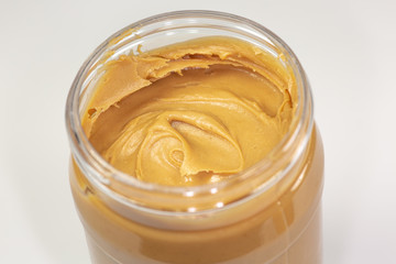 A jar of organic peanut butter sitting on the kitchen table waiting to be eaten 