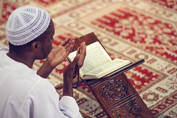 Fotobehang African Muslim Man Making Traditional Prayer To God While Wearing Dishdasha © FS-Stock