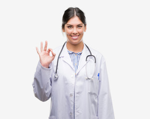 Young hispanic doctor woman doing ok sign with fingers, excellent symbol
