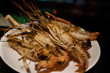 Close up of Grilled seafood, shrimps or prawn serving on white dish on pantry counter at seafood buffet restaurant 
