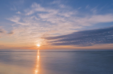 Obraz premium Tranquil sunrise over Avon By The Sea beach in New Jersey shot using slow shutter speed
