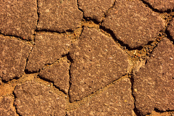 Cracks in the asphalt from above, warm colors
