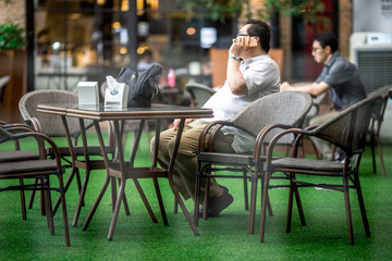 Bangkok: June 19, 2018, who work in Rama 4 area, sit (suanplernmarket), wait for friends and talk on the phone, Thailand