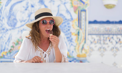 Middle age brunette woman eating ice cream with a confident expression on smart face thinking serious