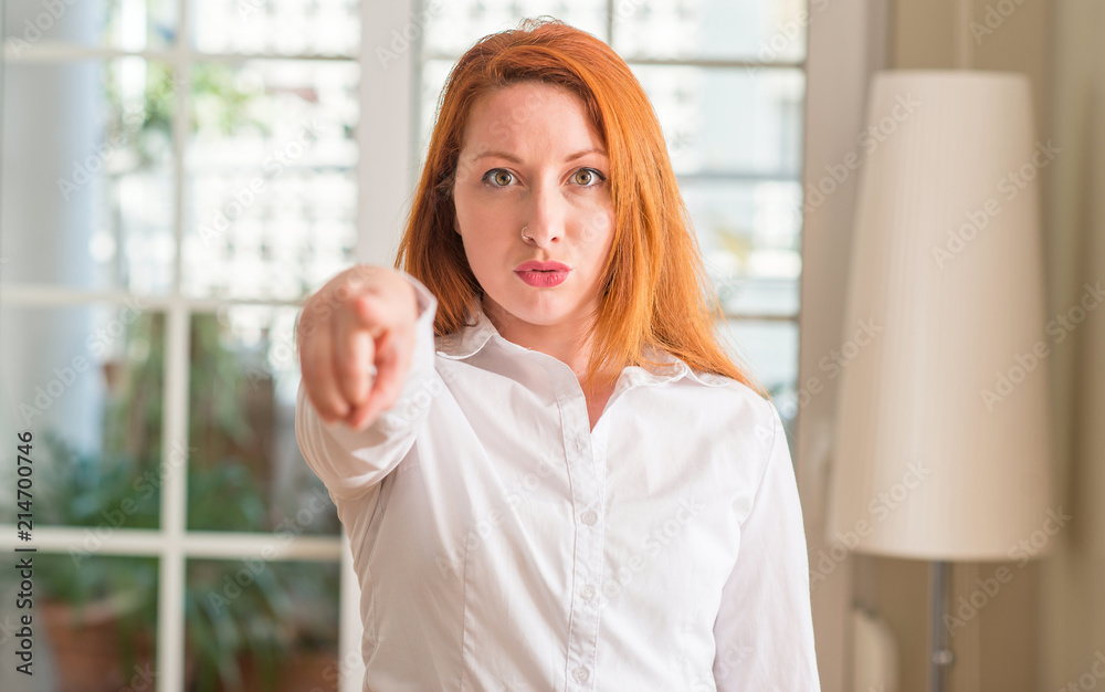 Sticker Redhead woman wearing white shirt at home pointing with finger to the camera and to you, hand sign, positive and confident gesture from the front