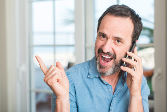 Middle age man using smartphone very happy pointing with hand and finger to the side
