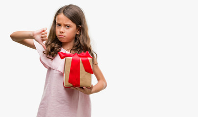 Fototapeta premium Brunette hispanic girl holding a gift with angry face, negative sign showing dislike with thumbs down, rejection concept