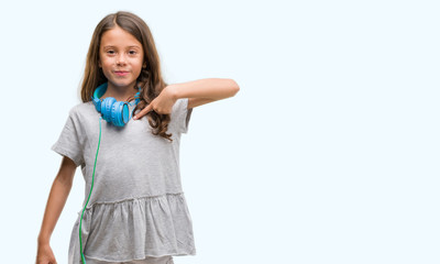 Brunette hispanic girl wearing headphones with surprise face pointing finger to himself