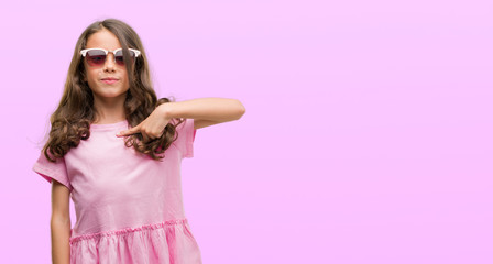 Brunette hispanic girl wearing sunglasses with surprise face pointing finger to himself
