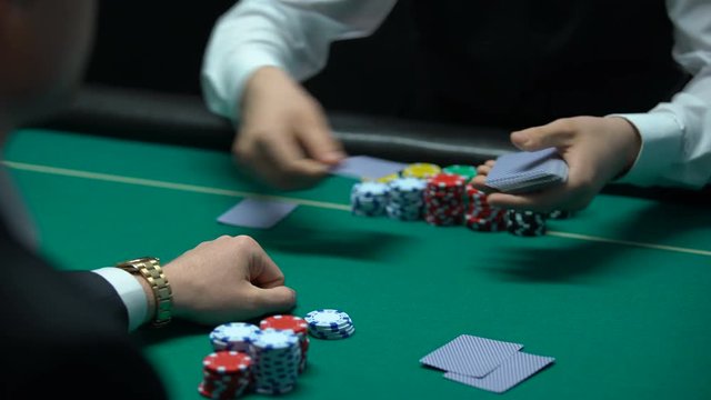 Male croupier dealing cards, player looking at bad combination, pair of deuces